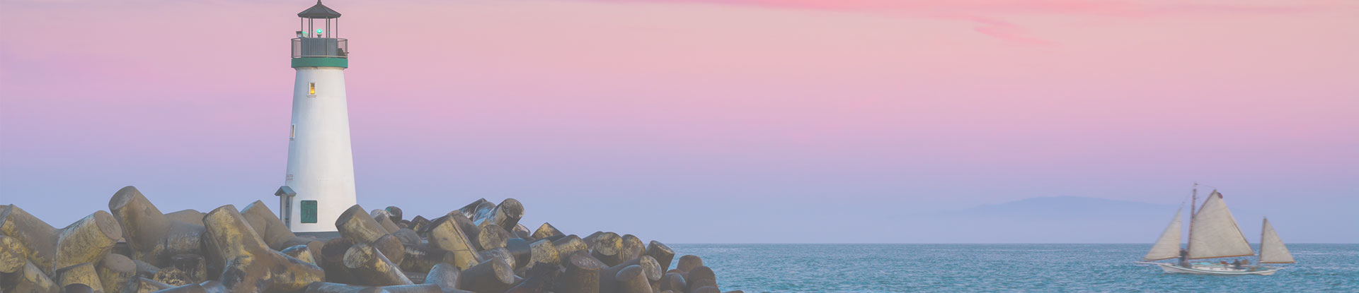 lighthouse on a rocky shore with sailboat nearby in the ocean