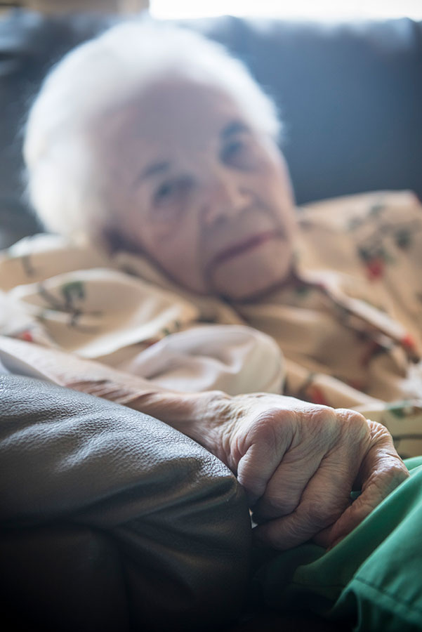 closeup of elderly person sitting in chair with focus on hand