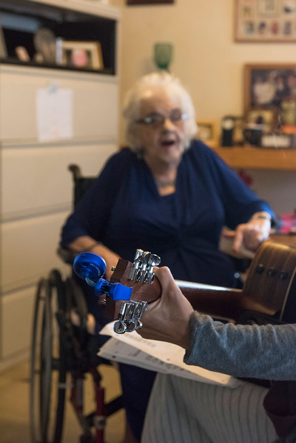 elderly person singing with a hand playing guitar in the foregound