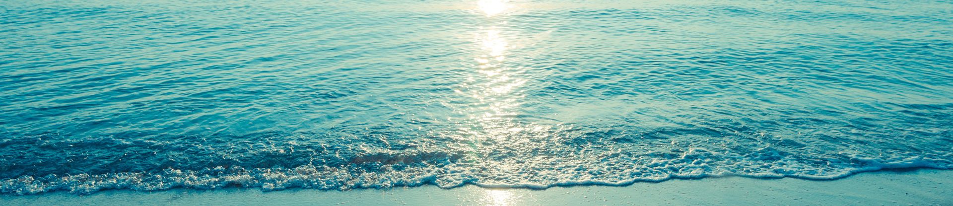 waves coming up on beach with reflected sun